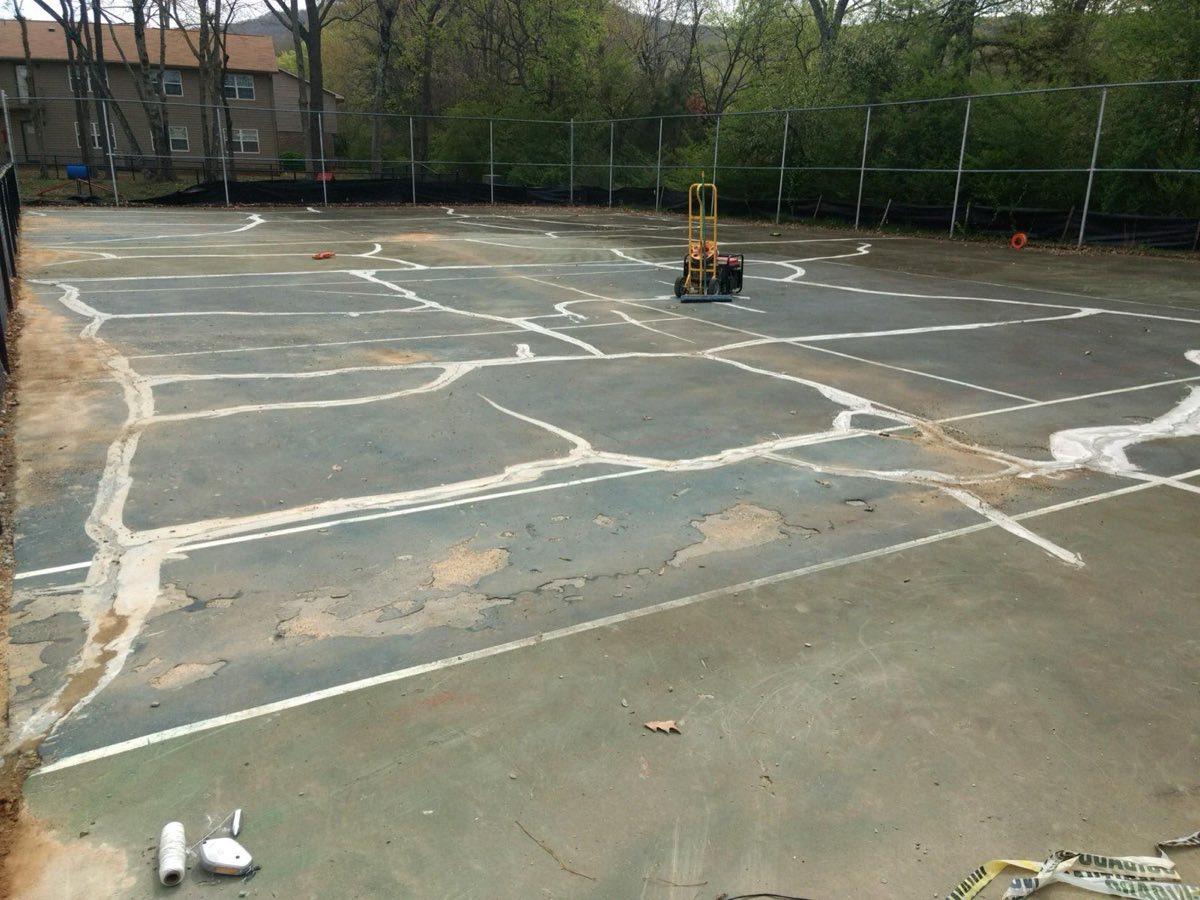 Hot-pour crack and joint sealant applied across a cracked court surface